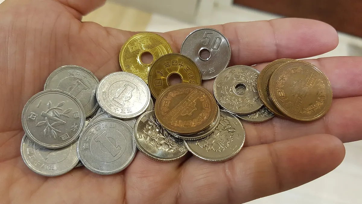 A hand holding a mix of Japanese yen coins